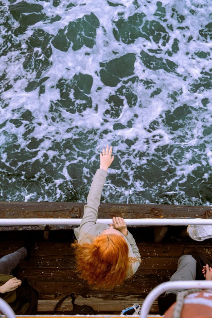 Femme sur le pont d'un bateau tendant la main vers la mer